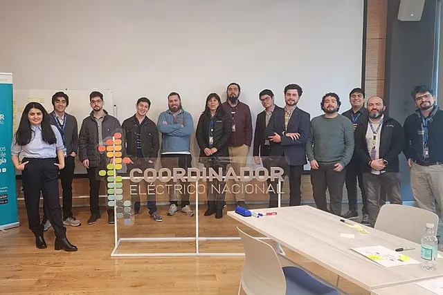 Un equipo posando junto al logo del Coordinador Eléctrico Nacional al terminar un taller