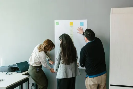 Tres integrantes de LeanSight acomodando notas adhesivas en un papelógrafo